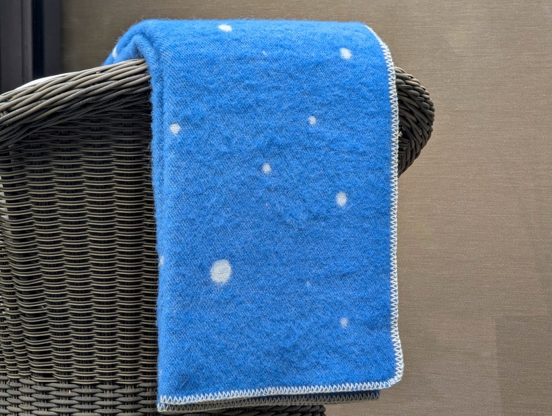 May include: A blue throw blanket with a white polka dot pattern, draped over a wicker chair.