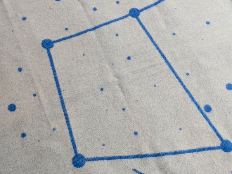 May include: A white fabric with a blue constellation pattern. The constellation is a square shape with five points.