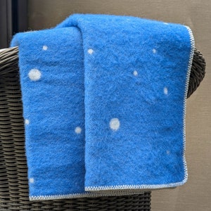 May include: A blue throw blanket with white polka dots, draped over a wicker chair.