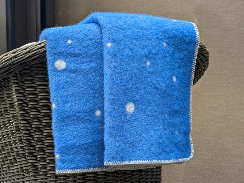 May include: A blue throw blanket with white polka dots, draped over a wicker chair.