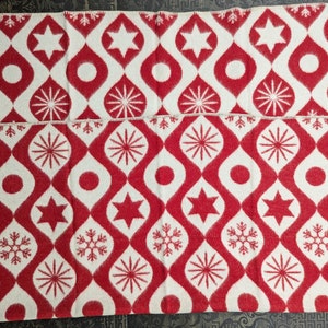 Puede incluir: Dos mantas estampadas en rojo y blanco. El dise&ntilde;o presenta un patr&oacute;n repetitivo de gotas, estrellas, c&iacute;rculos y copos de nieve rojos sobre un fondo blanco. Los bordes est&aacute;n acabados con un borde cosido blanco. Las mantas est&aacute;n dobladas y apiladas.