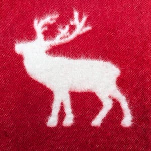 May include: White reindeer silhouette on a red fabric background.