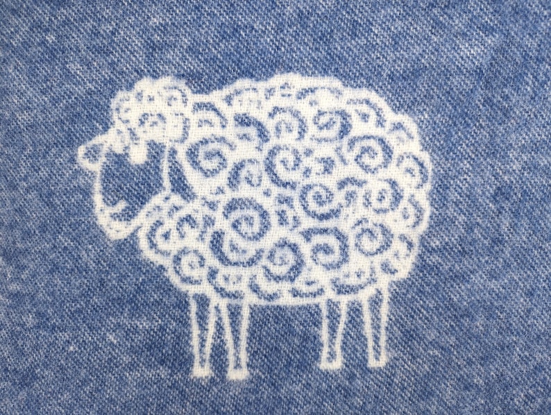 May include: A white sheep with a curly wool pattern is embroidered on a blue denim fabric.