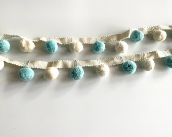 May include: A white trim with blue and white pom poms. The trim is made of a soft, woven fabric and is perfect for adding a touch of whimsy to any project.