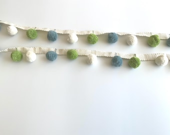 May include: Two rows of pom-pom trim in white, green, blue, and white. The pom-poms are attached to a cream-colored ribbon. The trim is ideal for adding a decorative touch to various craft projects, such as clothing, accessories, or home decor.
