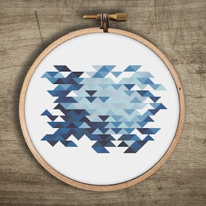 May include: A blue and white geometric pattern cross-stitch design in a wooden embroidery hoop.