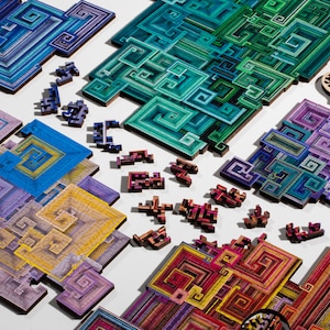 May include: A colourful jigsaw puzzle with geometric patterns in shades of blue, green, purple, and red. The puzzle pieces are scattered on a white surface.