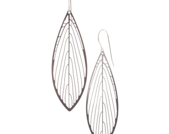 May include: A pair of silver leaf-shaped earrings with a delicate, intricate design. The earrings are made of metal and have a wire hook closure.