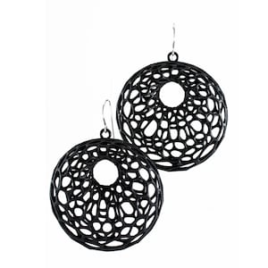 May include: A pair of black, circular earrings with a delicate, intricate web-like design. The earrings are made of a lightweight material and have a modern, geometric aesthetic.
