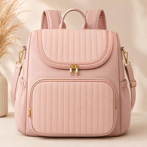 Puede incluir: Una mochila de color rosa claro que presenta un bolsillo frontal acolchado y una solapa superior a juego también acolchada. La bolsa incluye cremalleras metálicas doradas, correas ajustables para los hombros, un asa superior y bolsillos laterales.