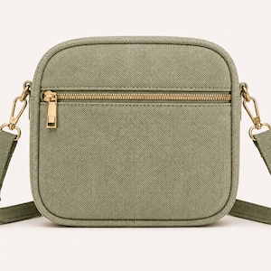 May include: A sage green crossbody bag with a textured fabric finish, featuring a rectangular shape with rounded corners, a horizontal front zipper pocket, gold-toned metal hardware, and an adjustable matching shoulder strap with metal clips.
