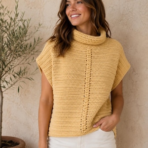 May include: A mustard yellow sleeveless crochet top featuring a high cowl neckline and a vertical braided cable stitch pattern running down the center front. The garment is constructed with a textured stitch throughout and has wide arm openings.