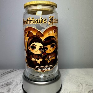 Op de afbeelding: Een glazen pot met een bamboe deksel en een zilveren voet. De pot heeft een afbeelding van twee cartoonmeisjes met een hart en de tekst "Bestfriends Forever".