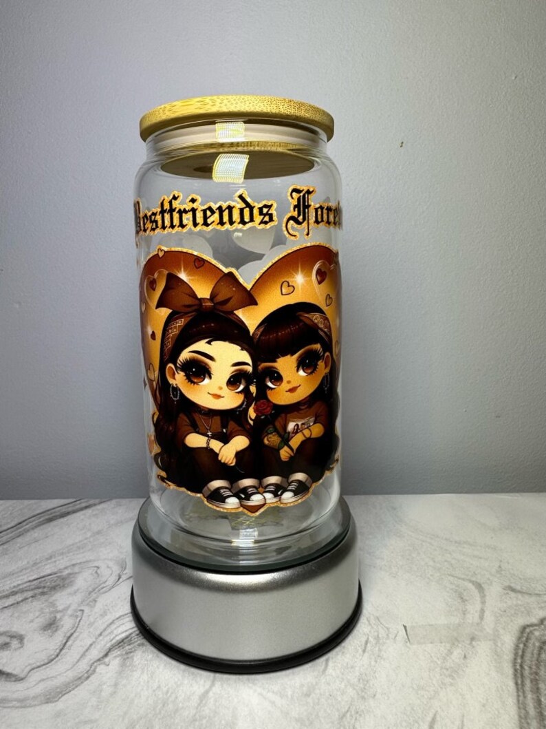Op de afbeelding: Een glazen pot met een bamboe deksel en een zilveren voet. De pot heeft een afbeelding van twee cartoonmeisjes met een hart en de tekst "Bestfriends Forever".