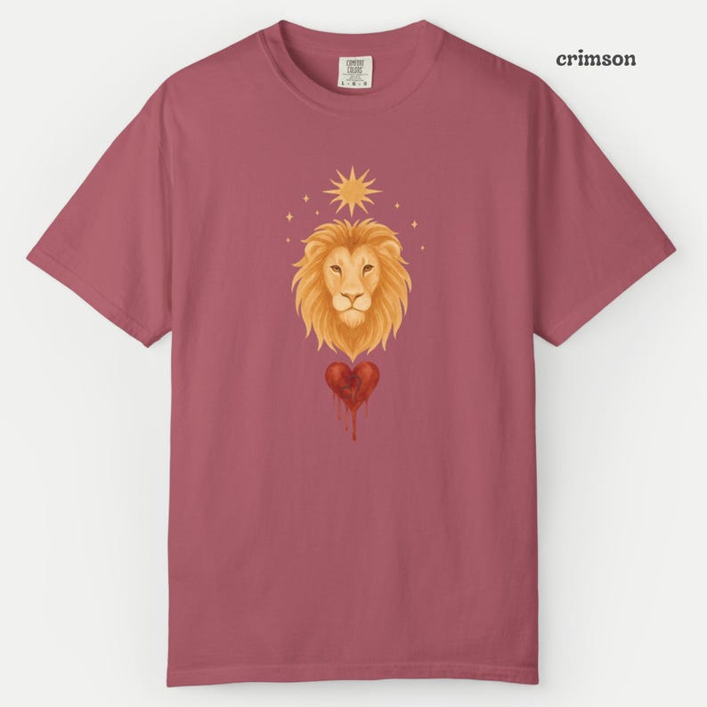 Comfort Colors Crimson t-shirt featuring a watercolor Leo lion head above a bleeding red heart with the Leo glyph, accented by a golden sun and stars.