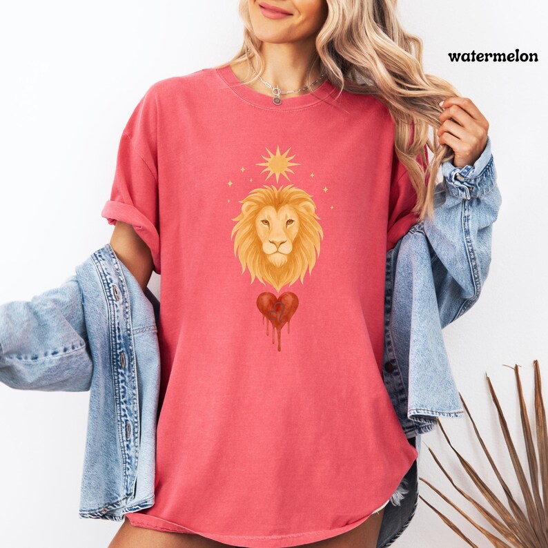 Model in a relaxed Comfort Colors Watermelon shirt with a soft Leo lion design, radiant sun, and a red bleeding heart centered on the chest.