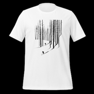 Pode incluir: Camiseta branca com um gráfico a preto e branco que retrata uma cena de floresta com esquiadores. O design mostra árvores altas e esquiadores numa encosta com neve, criando uma estética minimalista e ao ar livre. Ideal para quem gosta de esquiar e da natureza.