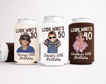 May include: Three foam can coolers in cream, white, and brown. Each features the text LOOK WHO'S followed by a number (30, 50, 40), a child's photo, and a name with the birthday milestone. The coolers are designed to fit standard beverage cans.