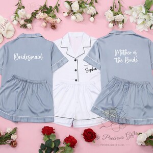 May include: Three matching pajama sets in blue and white with personalized text. The blue sets have white text that says "Bridemaid" and "Mother of the Bride". The white set has black text that says "Sophia".