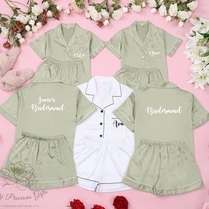 Könnte beinhalten: Set aus vier grünen Satin-Pyjamas mit weißen Verzierungen und personalisiertem Text. Die Pyjamas beinhalten "Junior Bridesmaid", "Bridesmaid", "Chloe" und "Grace".