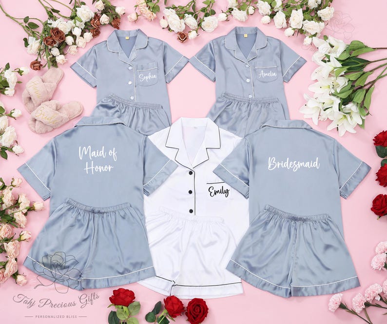 Puede incluir: Cuatro conjuntos de pijamas azul y blanco con mangas cortas y pantalones cortos. Las pijamas tienen texto blanco en la espalda que dice "Maid of Honor", "Bridemaid", "Emily" y "Amelia".