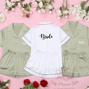Puede incluir: Tres conjuntos de pijama de sat&eacute;n a juego con mangas cortas y pantalones cortos. El conjunto de la novia es blanco con ribetes negros y dice "Bride" en escritura negra. Los otros dos conjuntos son verde salvia con ribetes blancos y est&aacute;n personalizados con nombres.