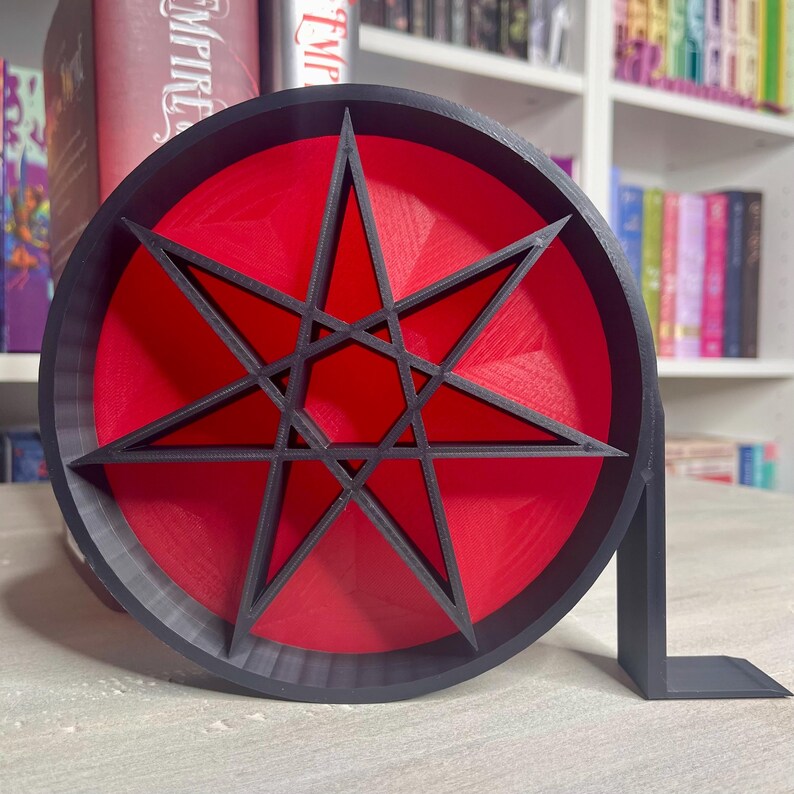 May include: A black and red 3D printed bookend shaped like an eight-pointed star. The star is outlined in black and has a red center.
