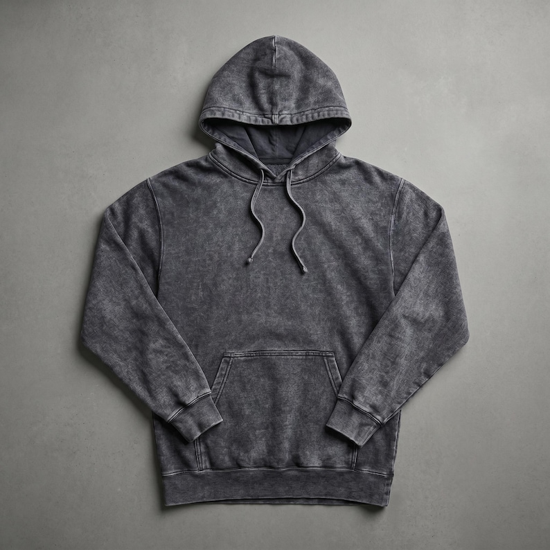 May include: A charcoal gray hoodie with a drawstring hood and a kangaroo pocket. The sweatshirt has a faded, textured appearance. The garment is laid flat on a gray surface.