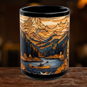 May include: Black ceramic mug featuring a scenic mountain and lake design. The artwork depicts a person in a canoe on a lake surrounded by trees and mountains. The mug has a black rim and base, with a detailed illustration in shades of brown, blue, and yellow.