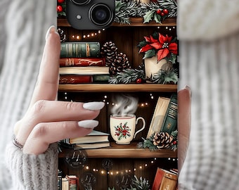 May include: A phone case featuring a cozy bookshelf design with books, poinsettias, pinecones, and a steaming mug. The case has a dark wood background with string lights and a festive holiday theme.