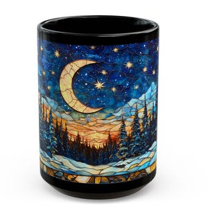 May include: Black ceramic mug featuring a stained-glass design of a crescent moon, stars, and a forest scene at sunset. The mug has a glossy finish and a black interior.