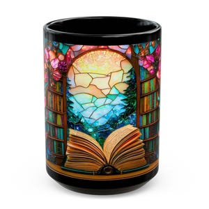 May include: Black ceramic mug featuring a stained-glass window design. The window depicts a landscape with a mountain, trees, and a bright sky, framed by bookshelves and flowers. An open book is at the bottom.