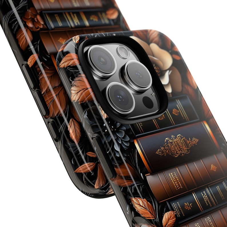 May include: Black phone case with a detailed design featuring stacks of books in shades of brown and gold. The case also has a floral and leaf pattern in brown and black, creating a vintage aesthetic.