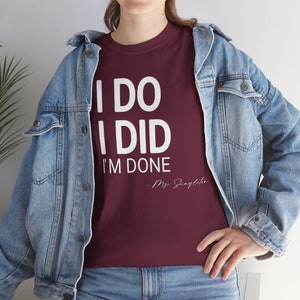 May include: A maroon t-shirt with white text that reads "I DO I DID I'M DONE - Ms. Singleton".