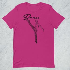 May include: A pink t-shirt with a black and white illustration of a person dancing. The text "Dance" is written in a stylized font above the illustration.