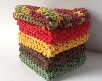 May include: A stack of six square, crocheted washcloths in various colors. The colors include green, brown, yellow, red, and a mix of green, yellow, and red. The washcloths are stacked neatly on top of each other.