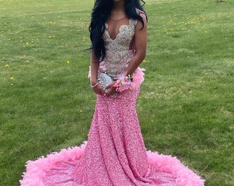 Vestido de fiesta de sirena con lentejuelas, corpiño de pedrería y ribete de plumas.