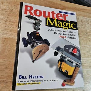 May include: A woodworking book titled "Router Magic" with images of routers. The cover features the title in red and yellow, with the author's name, Bill Hylton, and the tagline "Jigs, Fixtures, and Tricks to Unleash Your Router's Full Potential."