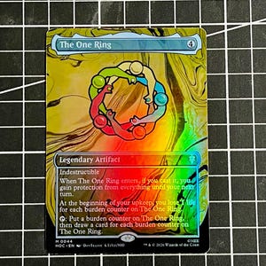 May include: A holographic Magic: The Gathering trading card titled The One Ring. The card features a circular illustration of colorful figures holding hands against a swirling gold and yellow background, with game text and a mana cost of 4.