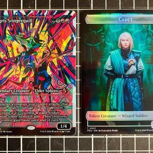 May include: Two collectible trading cards. The left card, Ingris Stingerquill, features a vibrant, abstract, multi-colored illustration of a creature. The right card, Cadet, depicts a blonde figure in blue attire with a dark, teal-toned background.