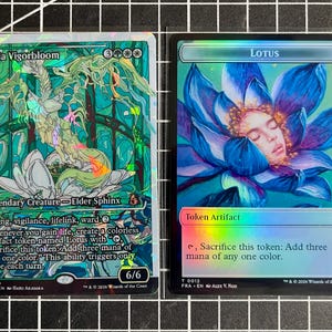 May include: Two holographic trading cards. The left card, Kwia Vigorbloom, features a green and white sphinx illustration with text detailing flying, vigilance, lifelink, and ward. The right card, Lotus, shows a blue flower with a face inside.