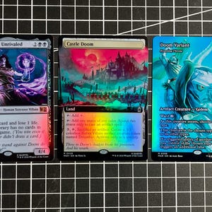 May include: Three Magic: The Gathering trading cards featuring Doctor Doom, Unrivaled, Castle Doom, and Doom Variant. Each card displays detailed character or landscape artwork with holographic foil finishes, text descriptions, and game statistics.