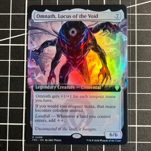May include: A holographic Magic: The Gathering trading card titled Omnath, Locus of the Void. The card features a dark, multi-limbed creature with a central eye, set against a vibrant, rainbow-colored background. It is a 6/6 Legendary Creature.