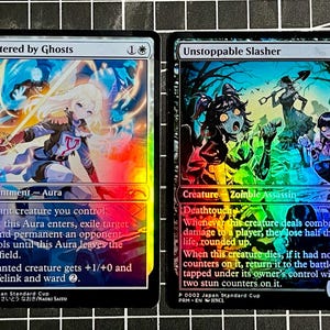 May include: Two holographic Magic: The Gathering trading cards. The left card is Sheltered by Ghosts, an enchantment aura featuring a blonde character. The right card is Unstoppable Slasher, a creature card depicting zombie figures in a dark forest.