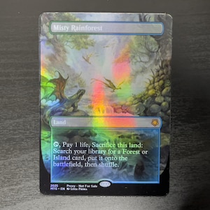 May include: A Magic: The Gathering card with a holographic finish. The card is blue and green with a picture of a misty rainforest. The card text reads "Misty Rainforest". Land. , Pay 1 life, Sacrifice this land: Search your library for a Forest or Island card, put it onto the battlefield, then shuffle.