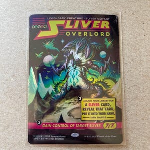 May include: A collectible card featuring the text "SLIVER OVERLORD" with a fantasy creature illustration. The card has a black background with green, blue, and purple accents. The card also includes game instructions and a 7/7 rating.