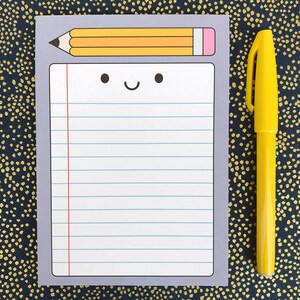 May include: A gray notepad with a lined page and a yellow pencil with a pink eraser on top. The notepad has a smiling face drawn on it.