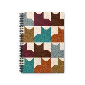 May include: Spiral-bound notebook featuring a repeating pattern of stylized cat silhouettes in various colors. The design includes teal, brown, orange, and burgundy cats on a cream-colored background. The notebook has a black spiral binding.
