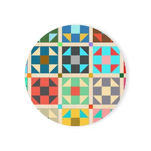 May include: A round, colorful design featuring a patchwork quilt pattern. The design includes squares with various geometric shapes in shades of blue, red, green, and yellow, set against a neutral background. The overall aesthetic is reminiscent of traditional quilting.
