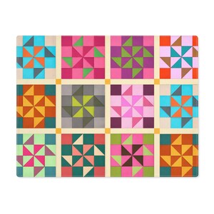 Puede incluir: Un mantel individual colorido con un diseño de patchwork con patrones geométricos. El diseño incluye cuadrados con triángulos y estrellas en tonos de azul, naranja, rosa, verde y morado, sobre un fondo crema.